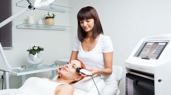 a specialist conducts a skin rejuvenation session with a device